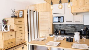 A modern kitchen with wooden cabinets, a central island with bar stools, and a built-in microwave.