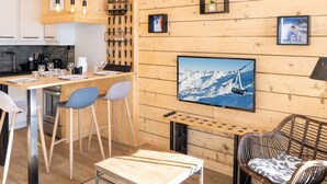 A modern kitchen with wooden walls, a bar area, and a large TV displaying a snowy mountain scene.