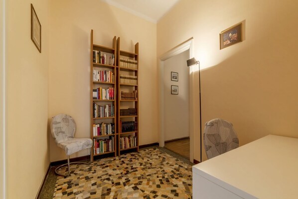 Una habitación con suelo estampado, una estantería, una silla y un escritorio.