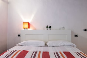 Een hotelkamer met een bed, een nachtkastje, een lamp en een kleine plant op het nachtkastje.