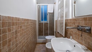 Une salle de bain avec douche, toilettes et baignoire.