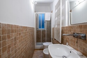 Une salle de bain avec douche, toilettes et baignoire.