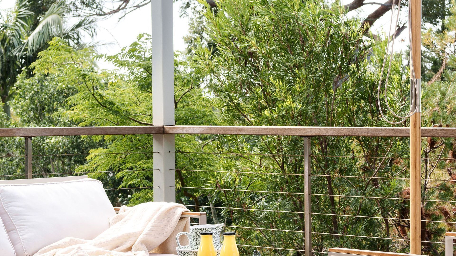 A balcony with a white sofa, a small table, and two yellow bottles.