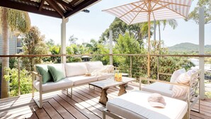 Una terraza de madera con un sofá blanco, una mesa de madera y un paraguas a rayas.