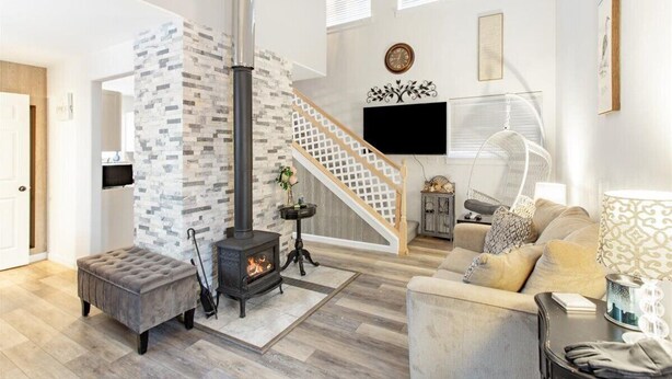 A modern living room with a fireplace, a staircase, and a sofa. - ★Serene & Stylish by the Lake | ♛QueenBed, FirePit (Talkeetna)