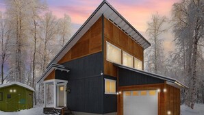 A modern two-story house with a dark exterior, large windows, and a garage. - ★Serene & Stylish by the Lake | ♛QueenBed, FirePit (Talkeetna)