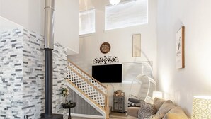 A spacious living room with a staircase, a fireplace, a flat-screen TV, and a comfortable seating area. - ★Serene & Stylish by the Lake | ♛QueenBed, FirePit (Talkeetna)