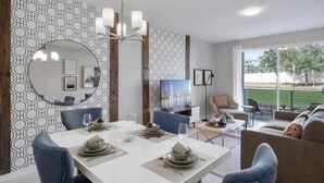 A modern dining area with a white table set for four, a large round mirror, and a patterned wall.