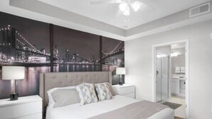 A modern bedroom with a large bed, two bedside tables, and a cityscape mural on the wall.