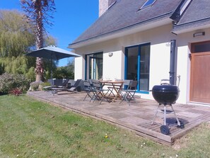 Un patio con mobiliario exterior, una parrilla de barbacoa y un área de estar techada.