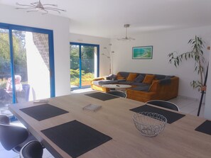 A modern living room with a sofa, a dining table, and a large window.