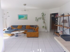 A modern living room with a sectional sofa, a coffee table, a potted plant, and a painting on the wall.