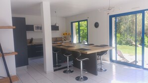 Eine moderne Küche mit einer zentralen Kochinsel, Barhocker und Blick ins Grüne.