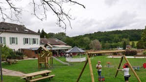 A playground with swings and a slide, surrounded by a wooden fence and picnic tables. - Bright 2-4 pers. loft with terrace and on-site restaurant (Lacroix-sur-Meuse)