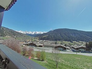 A mountain village with traditional buildings and a clear view of snow-capped peaks in the background.