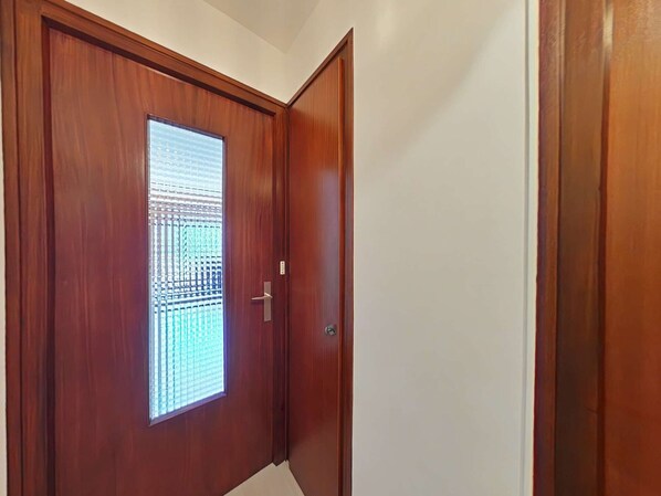 A wooden door with a window, a door handle, and a wall.