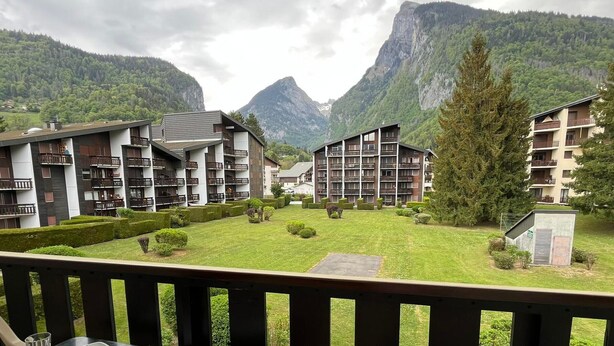 A balcony with a table set for two, overlooking a mountainous landscape with buildings in the background. - Cozy studio for 4, balcony, in Samoëns (Samoëns)