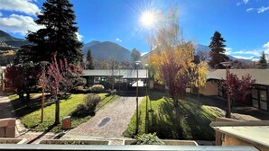 Un patio con un edificio, árboles y una montaña al fondo.