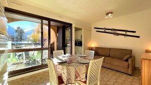 Un comedor con una mesa lista para cuatro personas, un sofá y un soporte para esquíes en la pared.