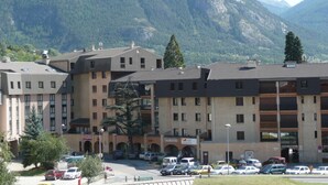 Un edificio de varios pisos con un patio central, rodeado de montañas.