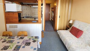 Ein kleines Zimmer mit Küchenzeile, Essbereich und Bett.