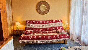 Ein Schlafzimmer mit einem Bett, zwei Nachttischlampen, einem runden Spiegel und einem Fenster mit Vorhängen.