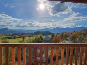 A view from a wooden balcony overlooking a mountainous landscape with autumn foliage, a clear sky, and distant mountains. - Studio for 4, south balcony, parking, calm residence (Saint-Michel-de-Chaillol)