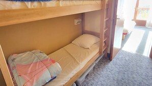 Ein Schlafzimmer mit Etagenbett, einem Holzbettgestell, einem kleinen Nachttisch und einem Fenster.