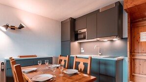 Una cucina moderna con un tavolo da pranzo in legno, sedie e un'isola blu.
