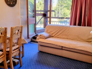 A cozy room with a sofa, a wooden chair, and a small table.