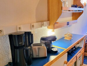 A kitchenette with a coffee maker, toaster, and a basket on the counter.