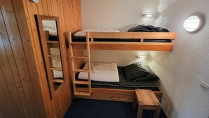 A bunk bed room with a wooden ladder, a small wooden bench, and a round window. - Ski-in studio with balcony, sleeps 4 (Les Arcs 1800)