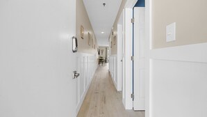 Un pasillo largo y estrecho con paredes blancas y suelo de madera.