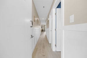 A long, narrow hallway with white walls and wooden flooring.