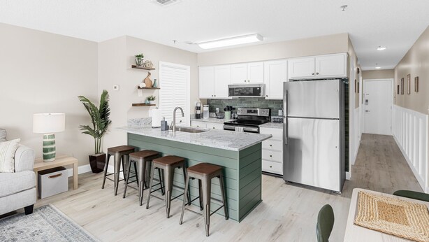 Una cocina moderna con una isla central, taburetes de bar y un refrigerador.