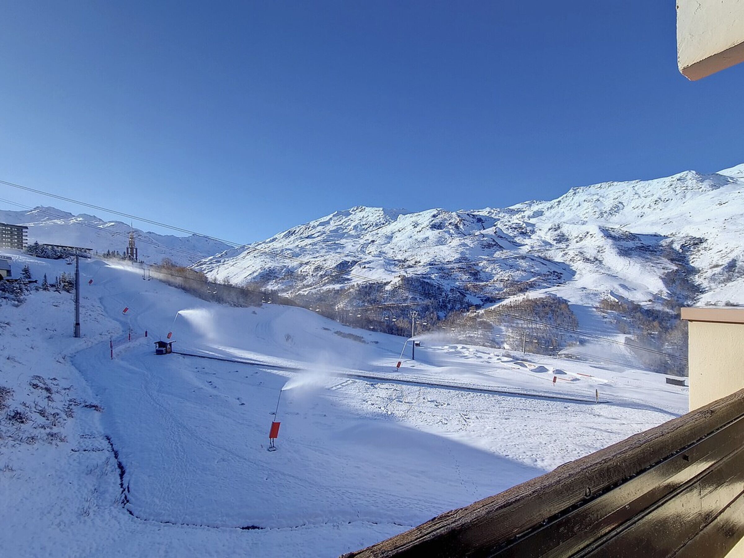 A snowy mountain slope with a ski lift and a building in the background.