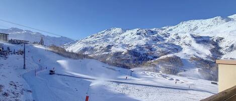 A snowy mountain slope with a ski lift and a building in the background.