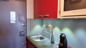 Una cocina compacta con microondas, hervidor y pileta.