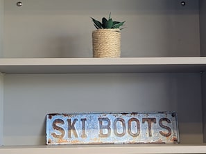 Une étagère avec une plante et une pancarte sur laquelle on peut lire : « CHAUSSURES DE SKI ».