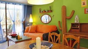 Een gezellige woonkamer met een groene muur, een houten eettafel met een kaars, en een cactus decoratie.