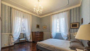 Un dormitorio con una cama, un aparador de madera, una silla y una araña.