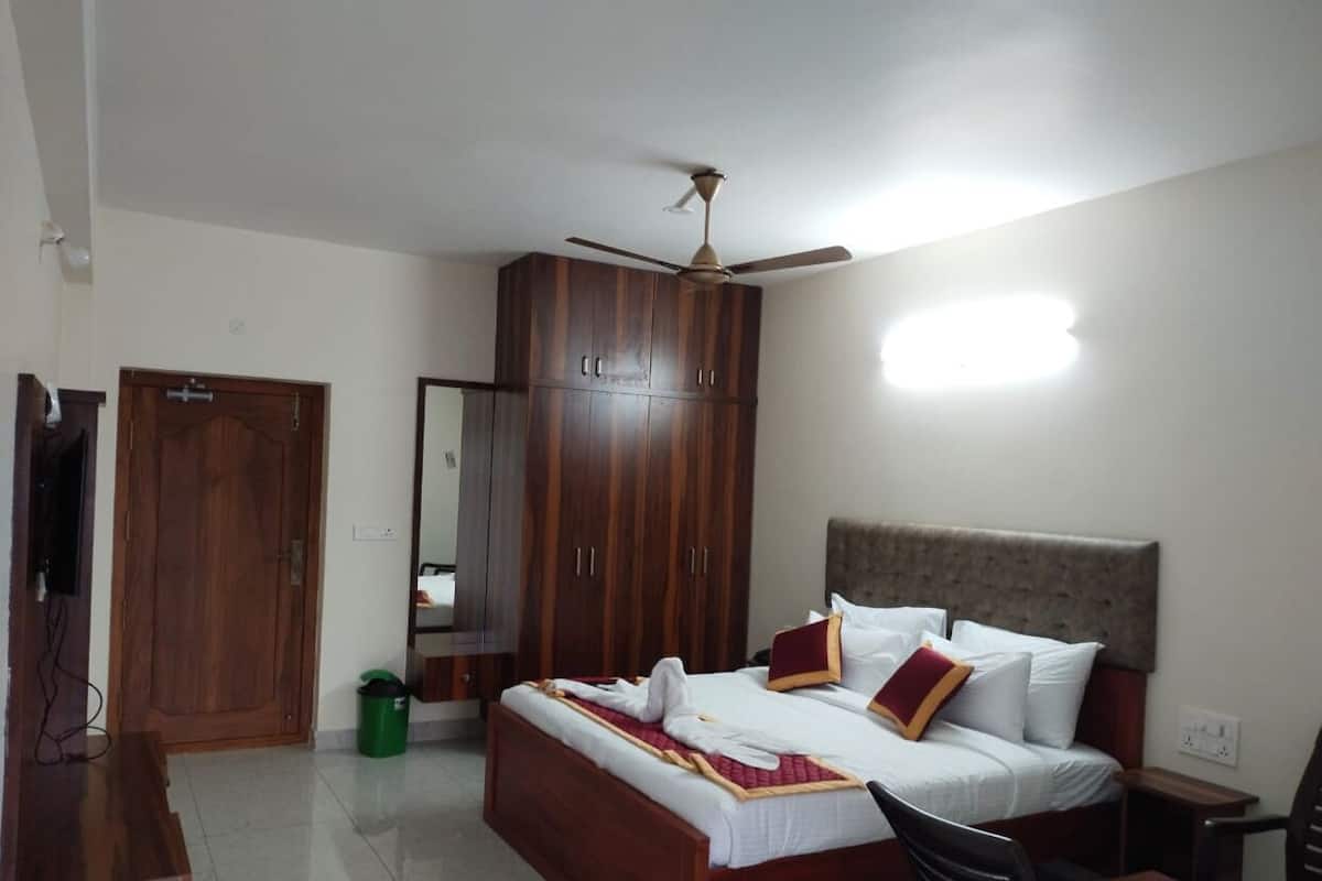 A bedroom with a bed, a ceiling fan, a wardrobe, and a mirror.