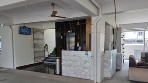 A reception area with a marble counter, a ceiling fan, and a staircase leading to an upper floor. - PPH Living KVR Residency (Tada)