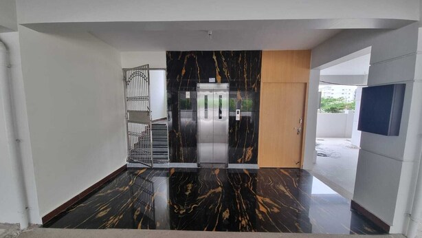 A modern interior with a marble floor, a metal gate, a wooden door, and a wall-mounted TV. - PPH Living KVR Residency (Tada)