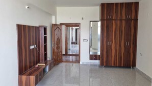 A hallway with wooden wardrobes, a ceiling fan, and a tiled floor. - PPH Living KVR Residency (Tada)