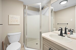 A modern bathroom with a glass-enclosed shower, a white toilet, and a sink with black faucets.