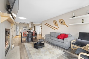 A modern living room with a grey sofa, red cushions, a coffee table, and a fireplace. - Tremblant Rocher Soleil Ski In Ski Out 2 Bedroom (Mont-Tremblant)