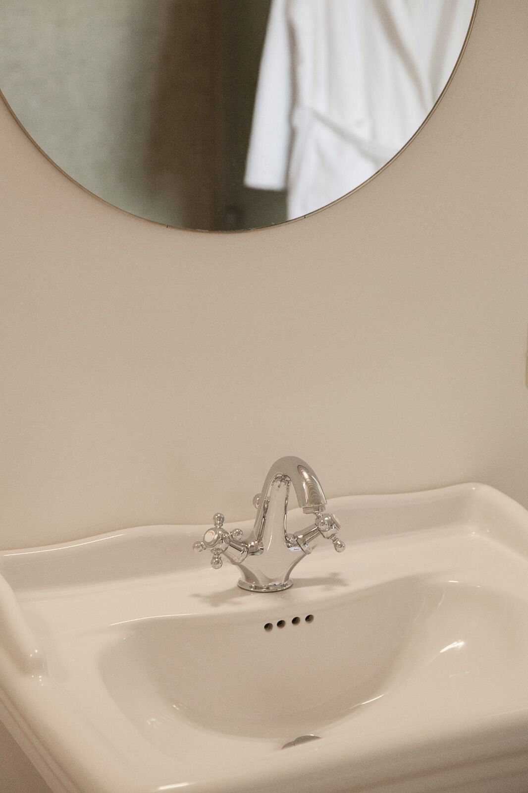 Un lavabo bianco con uno specchio rotondo sopra.