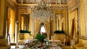 Une pièce somptueuse, ornée d’un grand lustre, de motifs dorés complexes et d’une table ronde dressée pour le dîner.