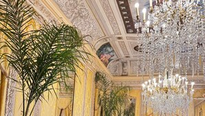 Une chambre luxueuse, ornée de moulures au plafond, dotée d’un magnifique lustre et d’un canapé moelleux.